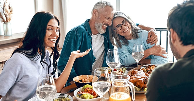 A family laugh and talk while eating dinner together.