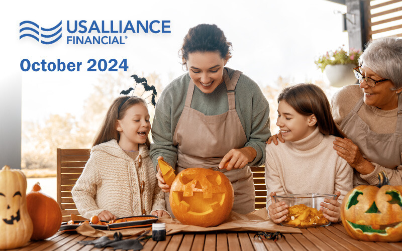 Family carving pumpkins together outdoors with "USALLIANCE FINANCIAL® October 2024" text.