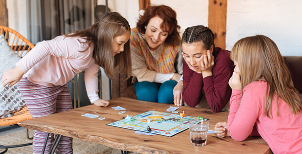 A family gather around the coffee table to play board games.