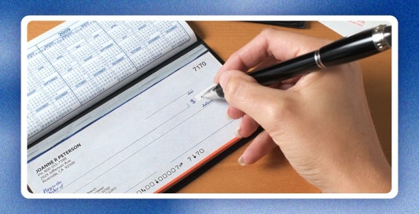 A person writing in their checkbook.