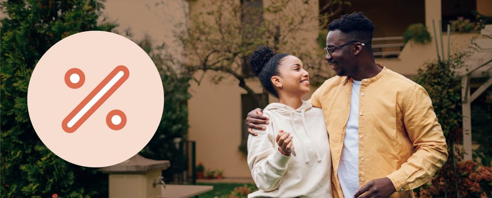 A man and woman hold their keys outside their new home.