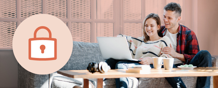 Couple on sofa with laptop and padlock icon in a living room.