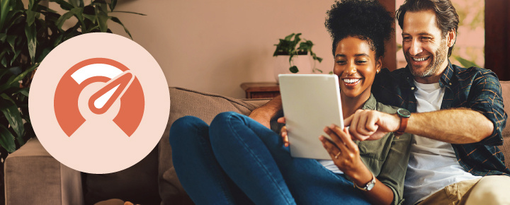 Couple smiling while looking at a tablet.