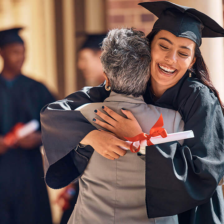 A girl in a graduation uniform hugging her family.