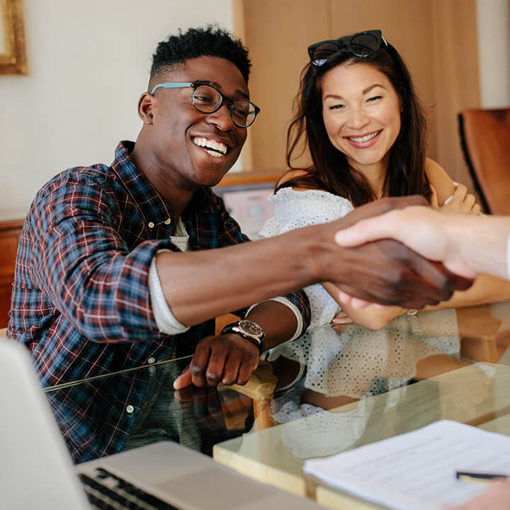 A couple shaking hands at their home closing.
