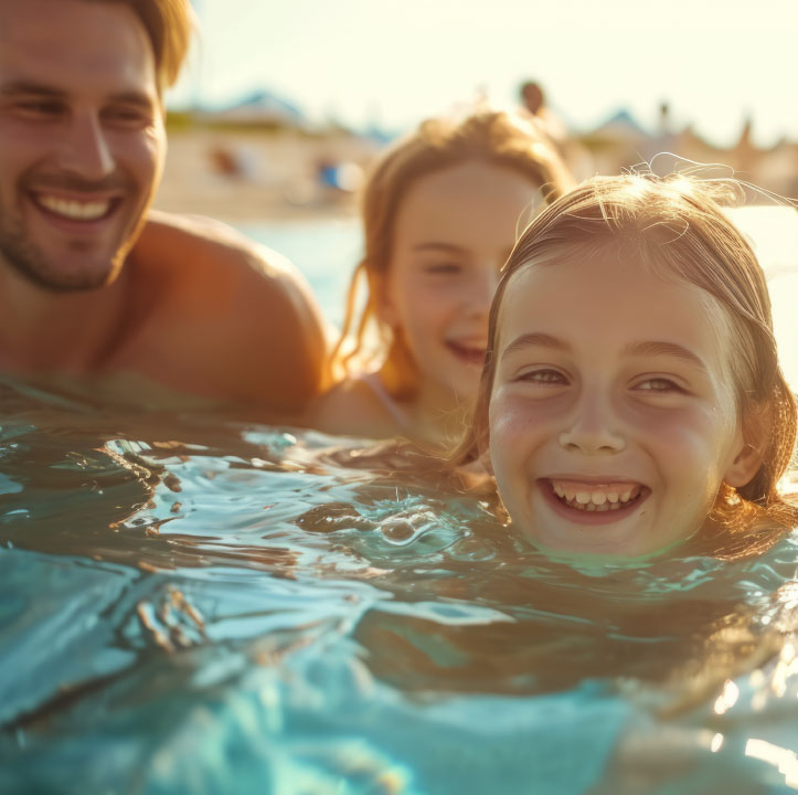 Family swimming in the ocean at a beach.