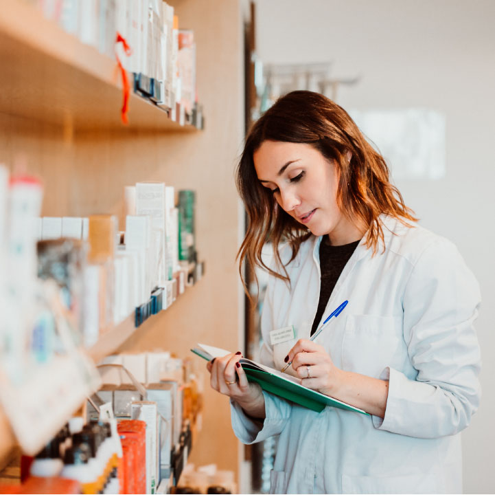 Young female pharmacist working in her large pharmacy. Placing medications, taking inventory.